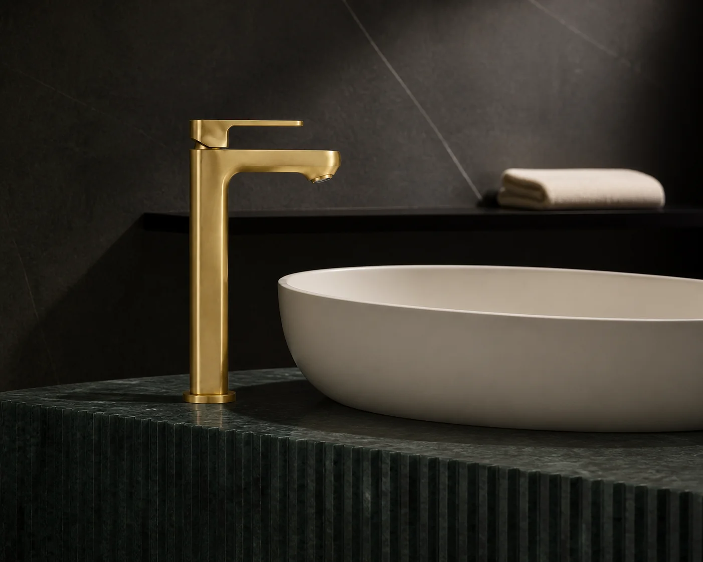 Side view of the brushed gold Tala Vessel mixer on a fluted deep teal vanity