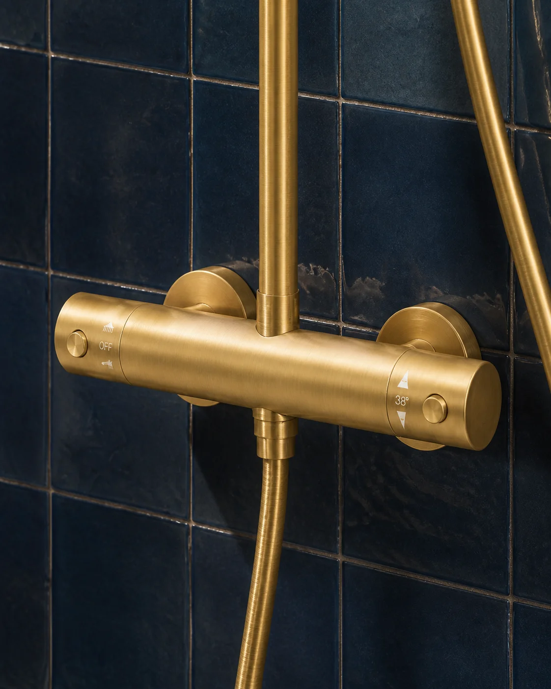 Detail of the brushed gold Rima thermostatic bar mixer against navy zellige