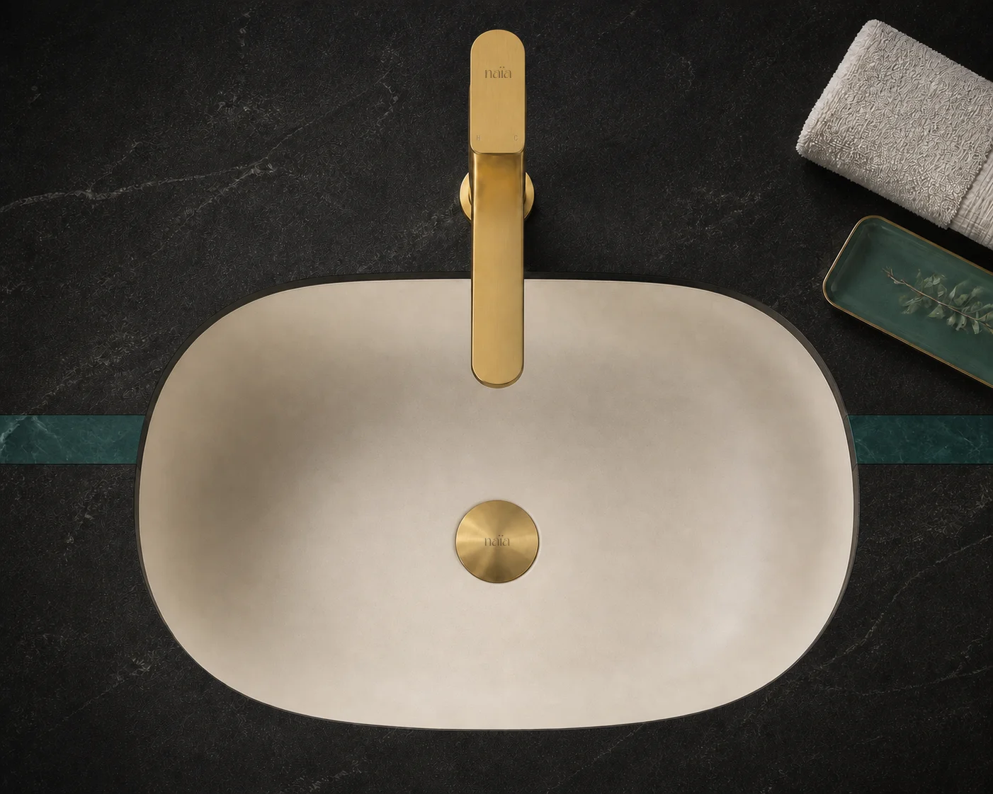 Top view of the brushed gold Tala Vessel mixer and matching waste in a cream bowl on black stone