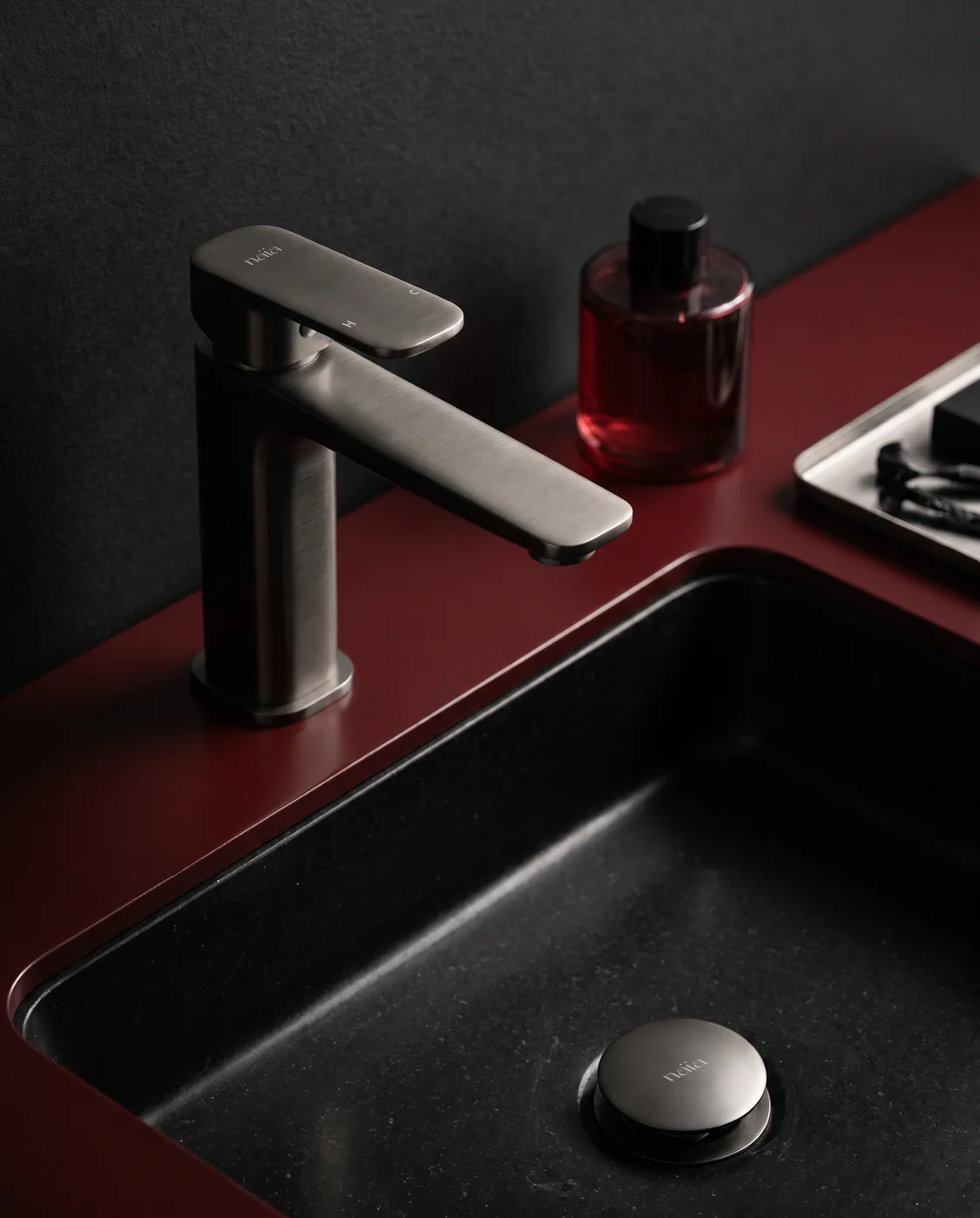 Gun grey Tala mixer with a black basin set into an oxblood counter
